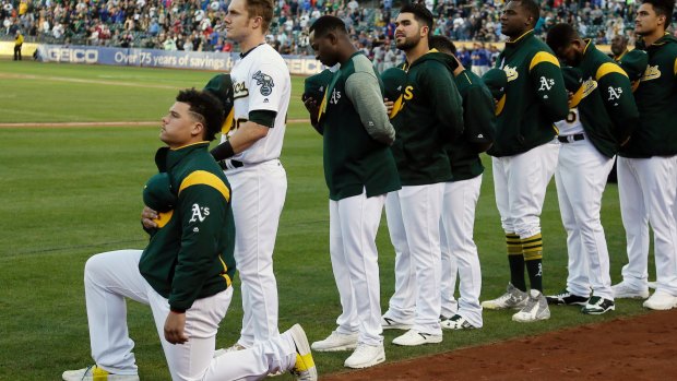 Oakland Athletics catcher Bruce Maxwell kneels during the National Anthem before the start of a baseball game against the Texas Rangers.