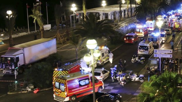 Emergency services vehicles work on the scene after a truck, left, ploughed through Bastille Day revellers in the French resort city of Nice.