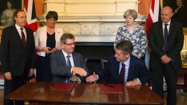 DUP MP Jeffrey Donaldson, sitting left, and government chief whip Gavin Williamson shake hands on the deal.