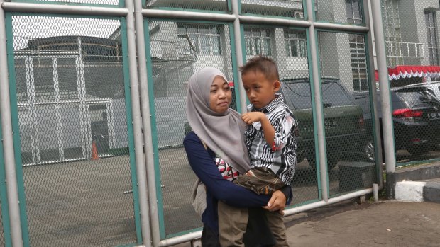 Yayah Heriyah, the wife of Syahrial, one of the cleaners jailed for alleged sex abuse at Jakarta Intercultural School, carries her son Muhammad Farid outside Jakarta's Cipinang prison.  