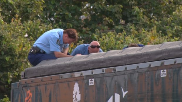 Police look into the back of the sand-blowing truck, where the man's body was found.