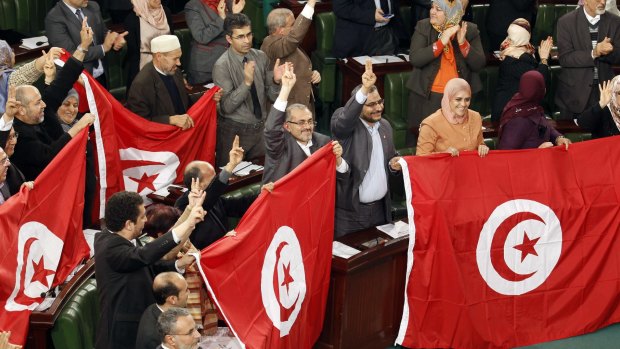 Tunisian MPs wave flags after approving the country's new constitution in the assembly building in Tunis last year. 