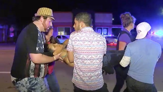 An injured person is escorted out of the Pulse nightclub in Orlando after being shot.