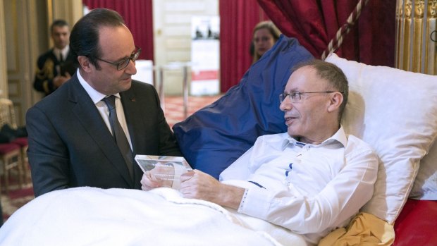 French President Francois Hollande talks with Claude Emmanuel Triomphe, who was injured in the Paris attacks.