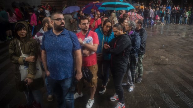 People in Barcelona queue in the rain to vote in the Catalan government referendum.