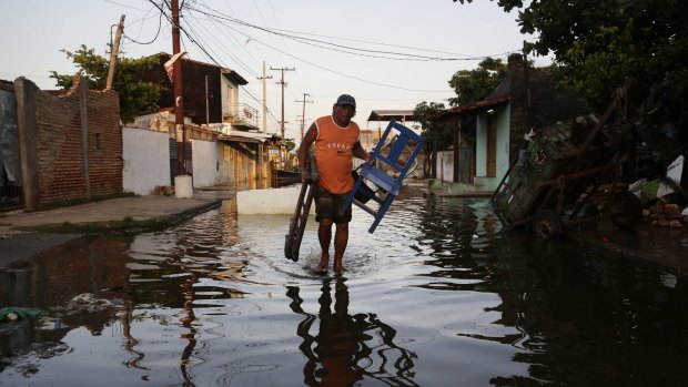 Saturnino Zorrilla carries chairs from his flooded home to a shelter in Asuncion, Paraguay. The Paraguay River is at its highest level since 1984.