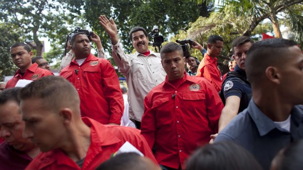 Flanked by security, Venezuelan President Nicolas Maduro waves to supporters in Caracas on Friday.