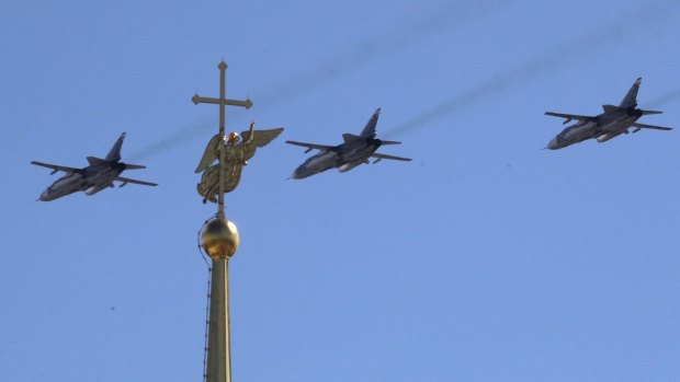 Sukhoy SU-24M military jets fly over a gilded weather vane in the form of an angel, fixed atop a spire of the Saints Peter and Paul Cathedral during a Naval parade rehearsal in St.Petersburg, Russia.