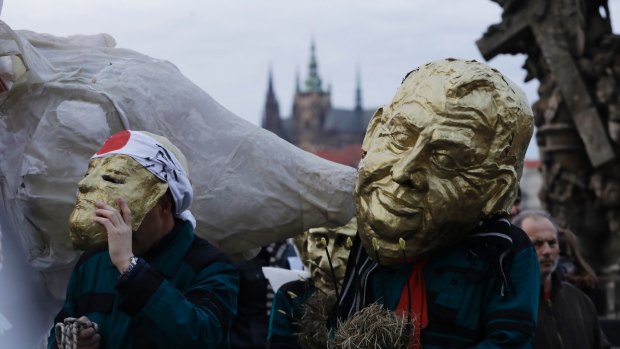 A man in a mask depicting Milos Zeman marches during commemorations for the anniversary of the Velvet Revolution.