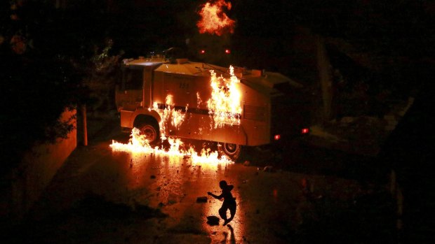 A man runs from a burning police vehicle during clashes between riot police and Kurdish militants in Van, eastern Turkey.