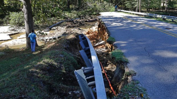 A man takes photos of an earthen dam damaged by floodwaters caused by rain from Hurricane Matthew in Fayetteville, North Carolina.