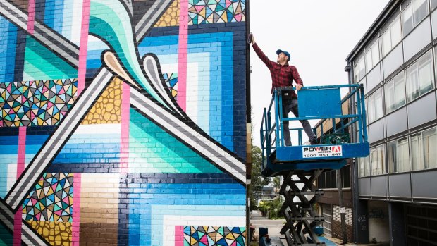 Street artist Bradley Eastman, aka Beastman, spray-paints a two-storey mural in St Leonards.