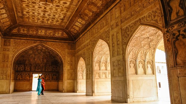 Two women walk in the ornate Agra Fort.