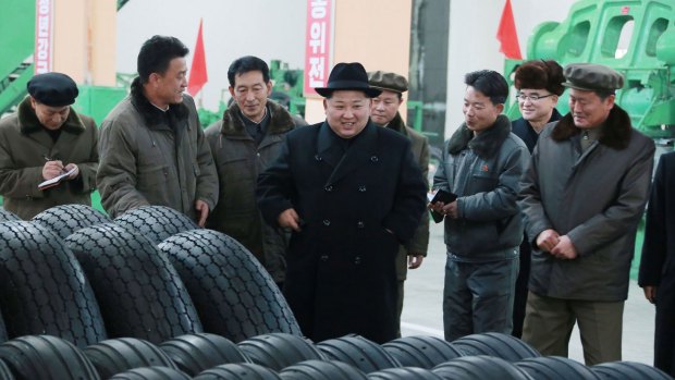 North Korean leader Kim Jong-un, centre, visits a local tire factory in Chagang Province to thank workers who built the tires for a huge vehicle used to transport the ballistic missile tested last week.