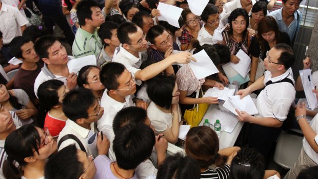 Jobseekers pass their resumes to representatives from Foxconn Technology Group at a job fair in Zhengzhou, Henan province.