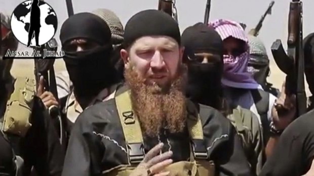 "Minister of war" Omar al-Shishani stands next to an IS spokesman among a group of fighters. The US said he was killed in March. 