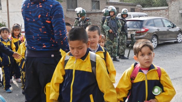 Children leave school under armed guard in Urumqi, Xinjiang, China.