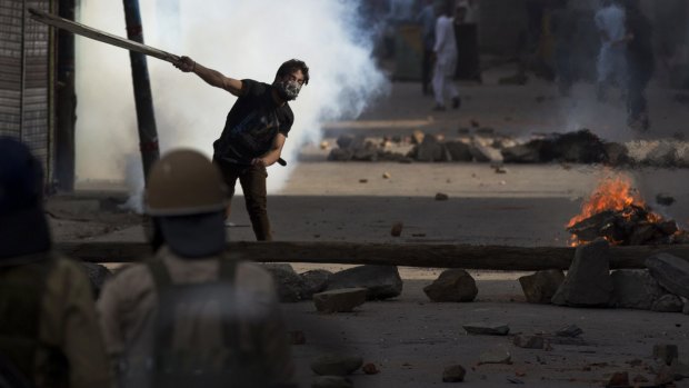 A Kashmiri Muslim protester throws a plank of wood at Indian policemen during a protest in Srinagar.