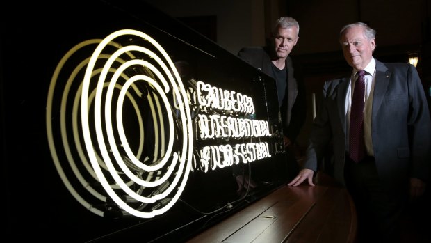 Canberra International Film Festival boardmember Cris Kennedy and general manager Andrew Pike with the neon sign made to promote the festival at the National Film and Sound Archive.