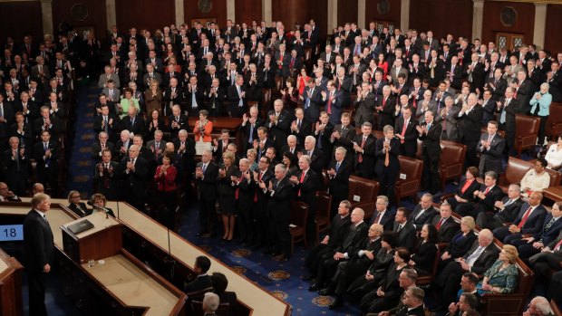Republicans Congressional members stand and applaud as Democratic members sit as US President Donald Trump pauses during his address.