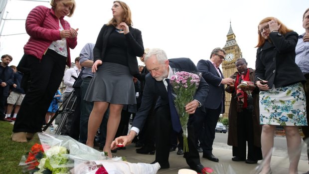 Labour Party leader Jeremy Corbyn, centre, lays a candle at an impromptu vigil at Parliament Square.