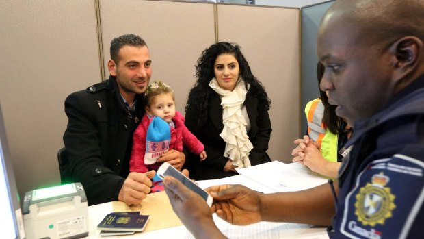 Border Services Officer processes a Syrian refugee family at Toronto Pearson International Airport.