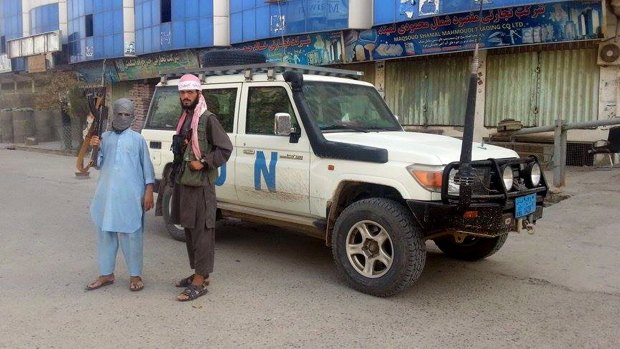 Taliban fighters pose for a photo next to a UN vehicle that they are using, in Kunduz, Afghanistan on Tuesday.