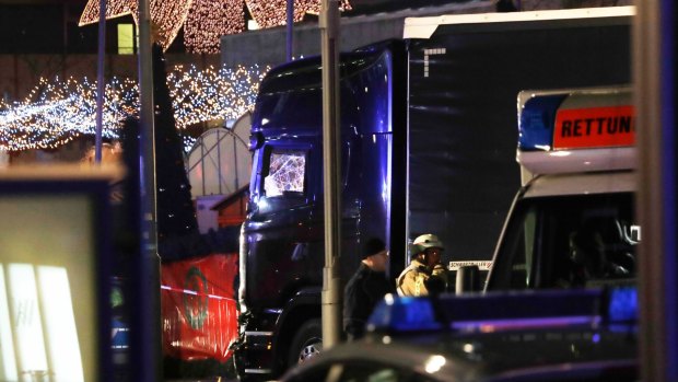 Police stand beside a damaged truck which ran into crowded Christmas market in Berlin.