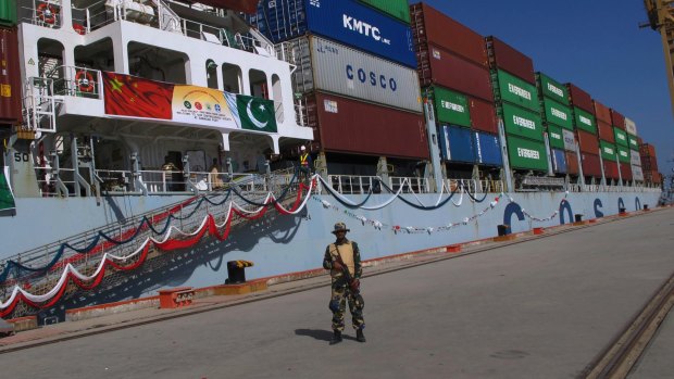 A Pakistan Navy soldier stands guard while a loaded Chinese ship prepares to depart from Gwadar port.