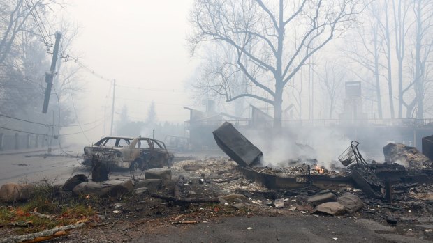 A structure and vehicle are damaged from the wildfires.