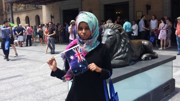Fatuma Ali Hussein waves an Australian flag after the citizenship ceremony at City Hall.