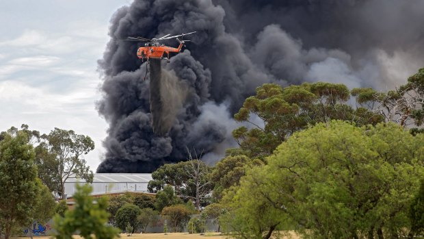 A water-bombing helicopter drops its load on the massive Broadmeadows tyre fire.