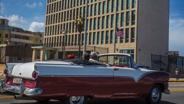 Tourists ride a classic convertible car on the Malecon beside the United States Embassy in Havana, Cuba.