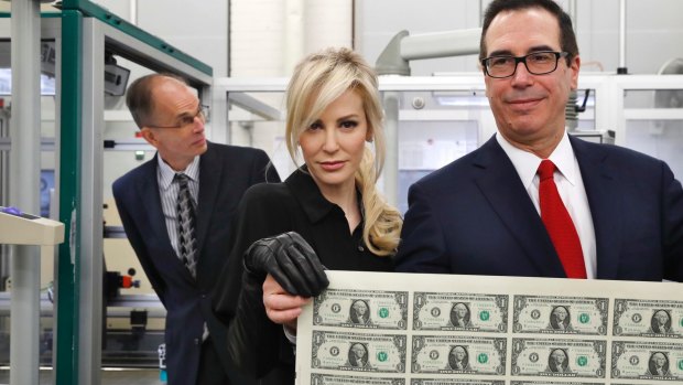 Treasury Secretary Steven Mnuchin, right, and his wife Louise Linton, hold up a sheet of new $US1 bills.