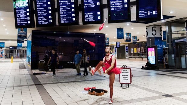 Sam Floyd aka 'Legs And His Magnificent Mind Bending Appendages' performs for early morning travellers at Flinders Street Station.