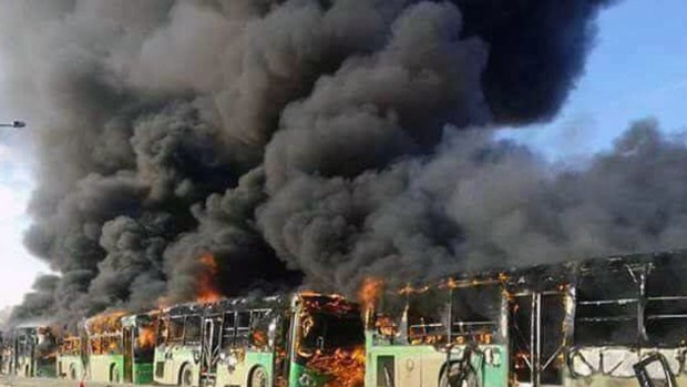 Smoke rises from green government buses awaiting to evacuate residents in Idlib province, Syria on Sunday.