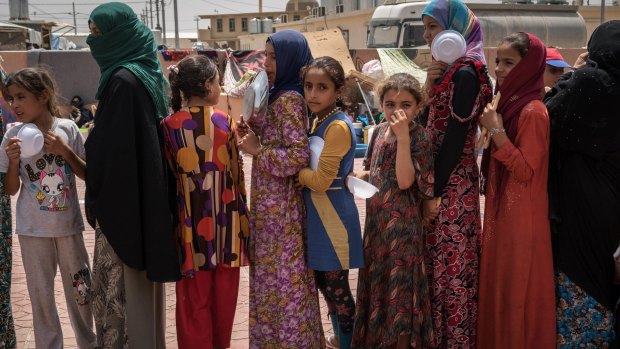 Women and children stand in line to receive a portion of food at Dibaga camp for internally displaced civilians in Iraq. 