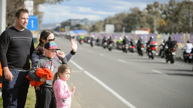 Shane Denaro, a police officer from Camden NSW, with his wife Shauna and children Lachlan, 10, and Indiana, 4, wave in support of the 2017 Ride for Remembrance as it makes its way down Northbourne Avenue. 
