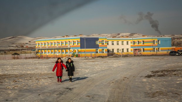 Coal smoke rises from a school's boiler as two girls walk home after class on the outskirts of Ulaanbaatar.