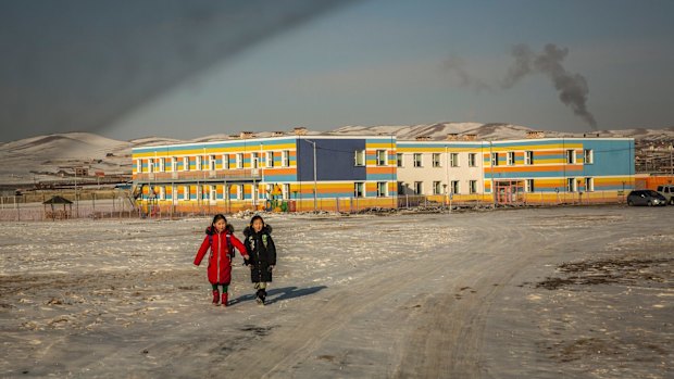 Coal smoke rises from a school's boiler as two girls walk home after class on the outskirts of Ulaanbaatar.