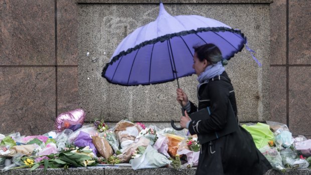 A woman walks past flowers and tributes left near the scene of Saturday's terrorist attack.