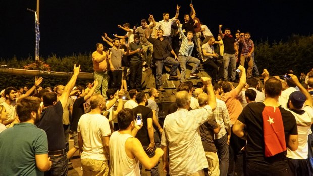 People gather on top of a Turkish army tank at Ataturk Airport in Istanbul.