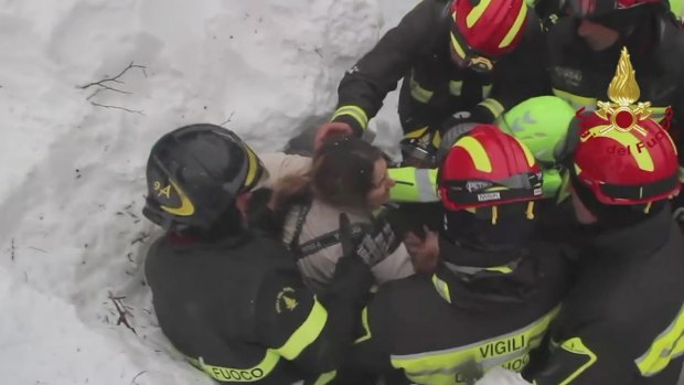 Italian firefighters rescue a woman from inside the buried hotel.