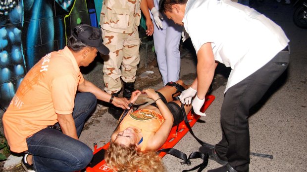 Rescue workers help an unidentified woman after one of the Hua Hin blasts earlier this month.