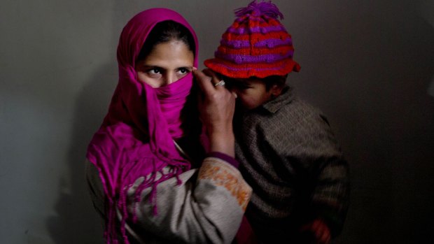 A Kashmiri woman holds her child as she waits to cast her vote.