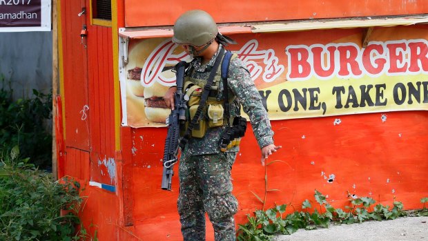 A Philippine marine signals his men to slow down as they near a corner at the frontline in Marawi city on Sunday.