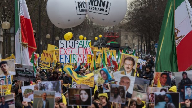 A demonstrator holds up a sign reading "Stop Executions in Iran" as Iranian opposition protesters march in Paris during the Iranian President's visit.