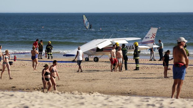 People walk past a small plane resting on the beach at Sao Joao beach at Caparica in Portugal.