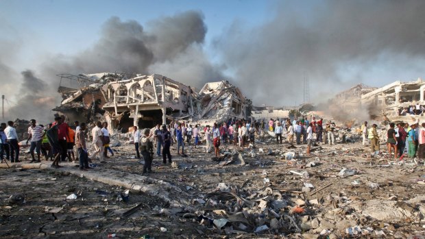 Somalis gather and search for survivors by destroyed buildings at the scene of a blast in Mogadishu, Somalia.