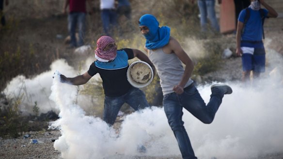 A Palestinian protester throws back a tear gas canister that was fired by Israeli troops during clashes near Ramallah, West Bank, on October Thursday.